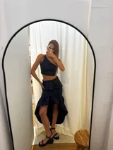 Pollera de tafeta color azul marino con diseño asimétrico de tipo high-low y volados. Presenta una cintura entallada y gran volumen en el ruedo.