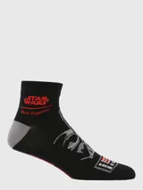 Calcetines cortos negros con diseño de la máscara de Darth Vader de Star Wars. Presentan el logo de Star Wars en rojo y la marca Hush Puppies en rojo en el borde superior. El talón es gris y la punta tiene detalles en rojo, gris y blanco que simulan la rejilla del casco.