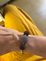 Pulsera dorada con tres piedras volcánicas negras y cierre corredizo.