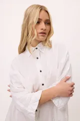 Vestido camisero a rayas verticales de colores pastel, con cuello camisero, cierre frontal con botones y mangas largas.