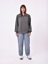 Buzo gris con cierre de cremallera en el cuello, de mangas largas y diseño holgado.