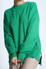 Sweater color beige de tejido de punto acanalado, con cuello redondo y mangas largas. Tiene corte holgado y aberturas laterales en el ruedo.