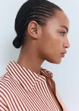 Camisa de manga larga con cuello camisero y cierre frontal de botones. Diseño recto con estampado de rayas verticales en tonos rojizos y beige.