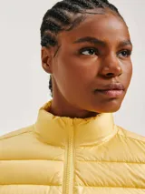 Campera puffer color crudo, confeccionada en poliéster con efecto matelassé, cuello alto y cierre frontal con cremallera.