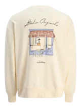 Buzo color crema de manga larga con cuello redondo y calce oversize. Estampa en la espalda con dibujo de una tienda y texto "Studio Originals" en la parte superior y "Daily Basics Worldwide" en la parte inferior.