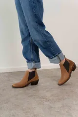 Botín negro de cuero con paneles laterales de gamuza y elástico en los tobillos. Tiene un pequeño taco cuadrado.