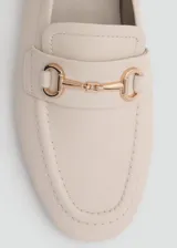 Mocasín de cuero color camel con punta fina y detalle de hebilla metálica dorada.