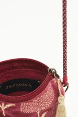 Bolso pequeño tipo cartera porta celular, confeccionado en terciopelo color borgoña con diseño bordado de tulipanes dorados. Tiene acceso superior con cierre y tirante en hilo metalizado, más cordón largo que permite colgarlo al cuerpo.