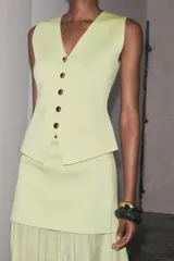 Falda midi color crudo, de tiro alto con cintura elástica y detalle de tejido combinado plisado y semitransparente. Cierre lateral con cremallera oculta en costura.