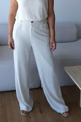 Pantalón de vestir ancho de tiro alto, color crudo con finas rayas verticales negras. Presenta pinzas frontales y cierre con botón visible.