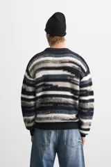 Jersey de hombre con corte relaxed, cuello redondo y manga larga. Diseño con patrón geométrico jacquard en tonos negro, gris y blanco.