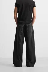 Pantalón de jean negro de corte amplio, con cinco bolsillos, efecto lavado y cierre frontal con cremallera y botón.