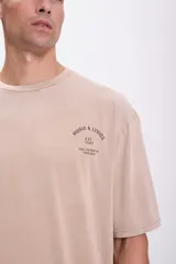 Remera color visón de corte amplio con estampa pequeña en el pecho.