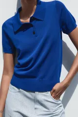Top azul eléctrico de punto, con cuello polo, manga corta y cierre frontal con botones negros.