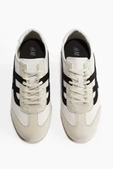 Zapatillas deportivas H&M color blanco con detalles en negro y beige. Confeccionadas en cuero sintético y gamuza, con cordones y suela de goma.