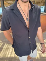 Camisa negra de algodón con textura waffle, corte clásico, cuello americano y botones color madera.