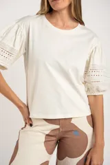 Remera negra de algodón con mangas 3/4 abullonadas con detalle de encaje calado. Corte al cuerpo.