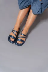 Sandalias chatas con tiras gruesas cruzadas en el empeine, color azul metálico.