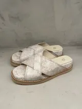 Sandalias bajas color blanco con textura craquelada y tiras cruzadas de cuero.
