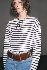 Camiseta de manga larga a rayas horizontales blancas y negras, con cuello redondo y bajo con aberturas laterales.