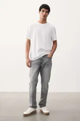 Jean gris de cinco bolsillos en denim de algodón elástico con cintura estándar y cierre con botón. Piernas rectas con buena libertad de movimiento en muslo y rodilla.
