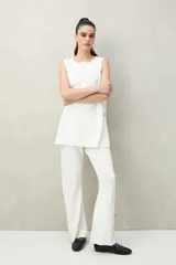 Pantalón negro de punto con calce relajado, caída fluida y botones dorados en los laterales.