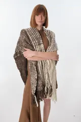 Ruana artesanal tejida en telar con lana hilada a rueca por tejedoras rurales de Uruguay. Diseño con patrón a cuadros en tonos marrón y crudo, con flecos en los extremos.