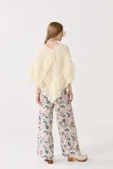 Poncho color crudo de lana merino, con flecos bordados a mano en el ruedo y escote en V.