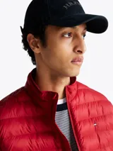 Campera acolchada roja de Tommy Hilfiger, con cuello alto y cierre de cremallera. Cuenta con dos bolsillos laterales con cremallera y logo bordado en el pecho.
