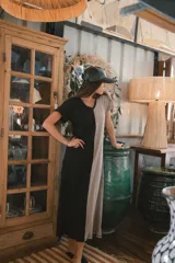 Vestido largo de tejido acanalado, con diseño bicolor vertical: mitad negro y mitad beige claro. Tiene mangas cortas y escote en V.