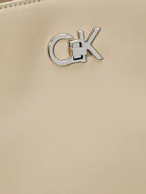 Cartera tipo saco de piel sintética estructurada color beige, con correa ajustable para el hombro y herrajes plateados. Presenta el monograma de Calvin Klein en la parte frontal.