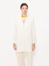 Saco color crema confeccionado en algodón, con bolsillos ojal, hombreras y aplique Groovy en el cuello.