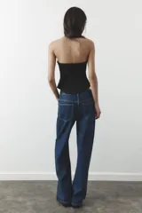 Pantalón de jean azul oscuro, de corte wide leg y tiro medio, con cinco bolsillos y cierre frontal con cremallera y botón metálico.