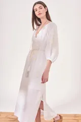 Vestido túnica largo color blanco, con escote en V, mangas 3/4 y bordado floral en el frente y las mangas. Incluye lazo de ajuste en la cintura con borlas.