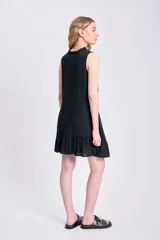 Vestido corto negro sin mangas, confeccionado en lino, con escote redondo con lazo y volados en el ruedo.