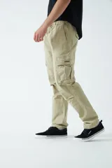Pantalón cargo color beige, con cintura elástica ajustable con cordón, bolsillos laterales con cierre y bolsillos cargo con solapa.