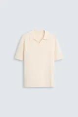Polo color crema de punto, corte regular fit, con cuello solapa y abertura frontal.