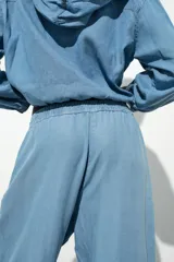 Pantalón jogger celeste confeccionado en lino, con tiro alto, cintura elástica ajustable con cordón, bolsillos delanteros y puños elásticos en el bajo.