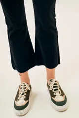 Pantalón de pana negro, tiro medio, corte ajustado hasta la rodilla y acampanado en la parte inferior, con terminación desflecada.