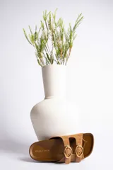 Sandalias de cuero color beige con dos tiras anchas y hebillas doradas ajustables.