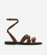 Sandalias planas de cuero color marrón, con múltiples tiras finas ajustables con hebillas doradas. Tira que se ata al tobillo.