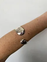 Brazalete rígido plateado con terminaciones redondeadas e irregulares.