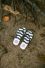 Chancletas blancas con estampado de ondas negras y tiras negras.