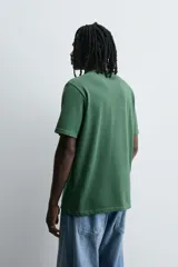 Camiseta verde oscuro de corte relaxed fit, cuello redondo, manga corta y bolsillo plastrón en el pecho.