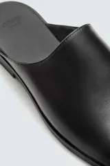 Zueco negro de cuero con punta redondeada y suela plana.