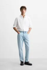 Pantalón de jean celeste de corte slim fit y tapered, con cinco bolsillos, efecto lavado y cierre frontal con cremallera y botón.