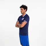 Polo deportivo azul marino con cuello tipo camisa y tres botones. Los bordes de las mangas y el cuello tienen detalles de rayas blancas y rojas. Lleva el escudo del Club Nacional de Football bordado en el pecho.