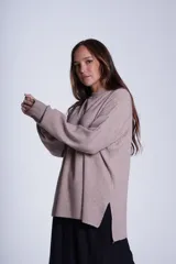 Sweater color beige de tejido de punto acanalado, con cuello redondo y mangas largas. Tiene corte holgado y aberturas laterales en el ruedo.