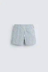 Bañador de hombre confeccionado en tejido técnico con textura. Diseño a rayas verticales en tonos azul y blanco. Cintura elástica ajustable con cordón. Bolsillos laterales y detalle de bolsillo trasero de solapa. Bajo con aberturas laterales. Forro interior.