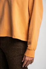 Sweater color naranja con cuello polo y botones, de corte holgado y mangas largas.